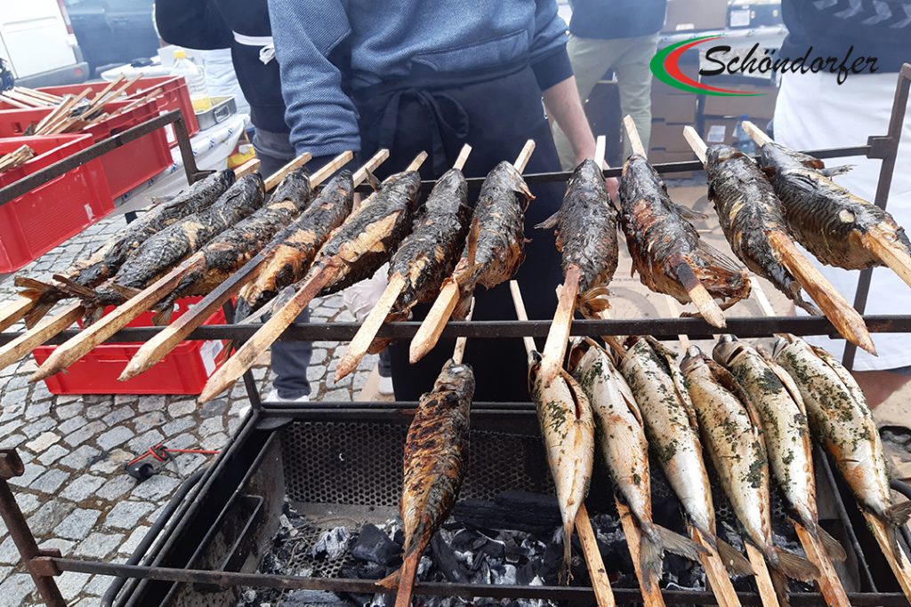 Fisch Großhandel Produkte: Steckerlfisch auf Holz gespielßt über dem Grillfeuer.